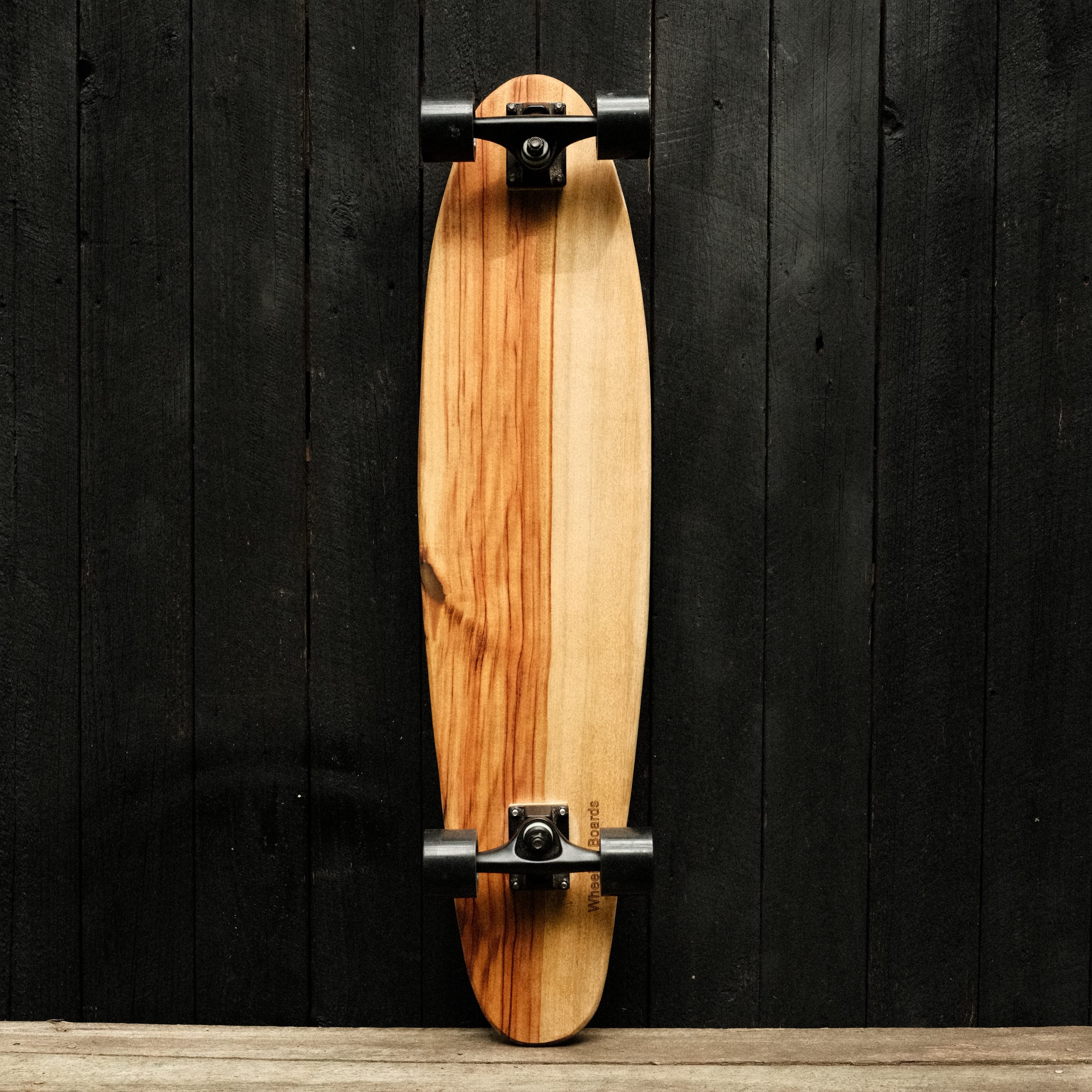 Back of a longboard skateboard with trucks and wheels in black