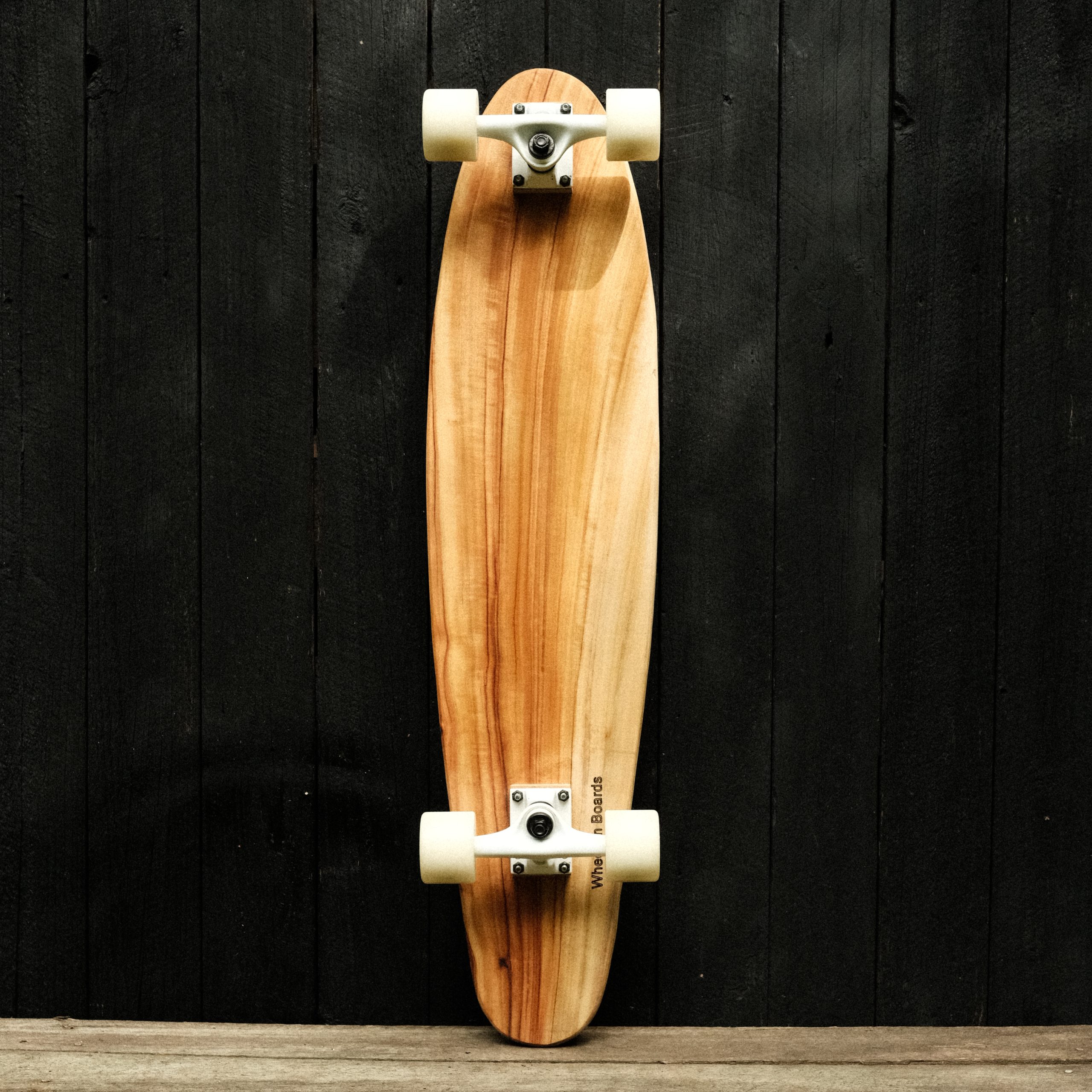 Back of a longboard skateboard with trucks and wheels in white