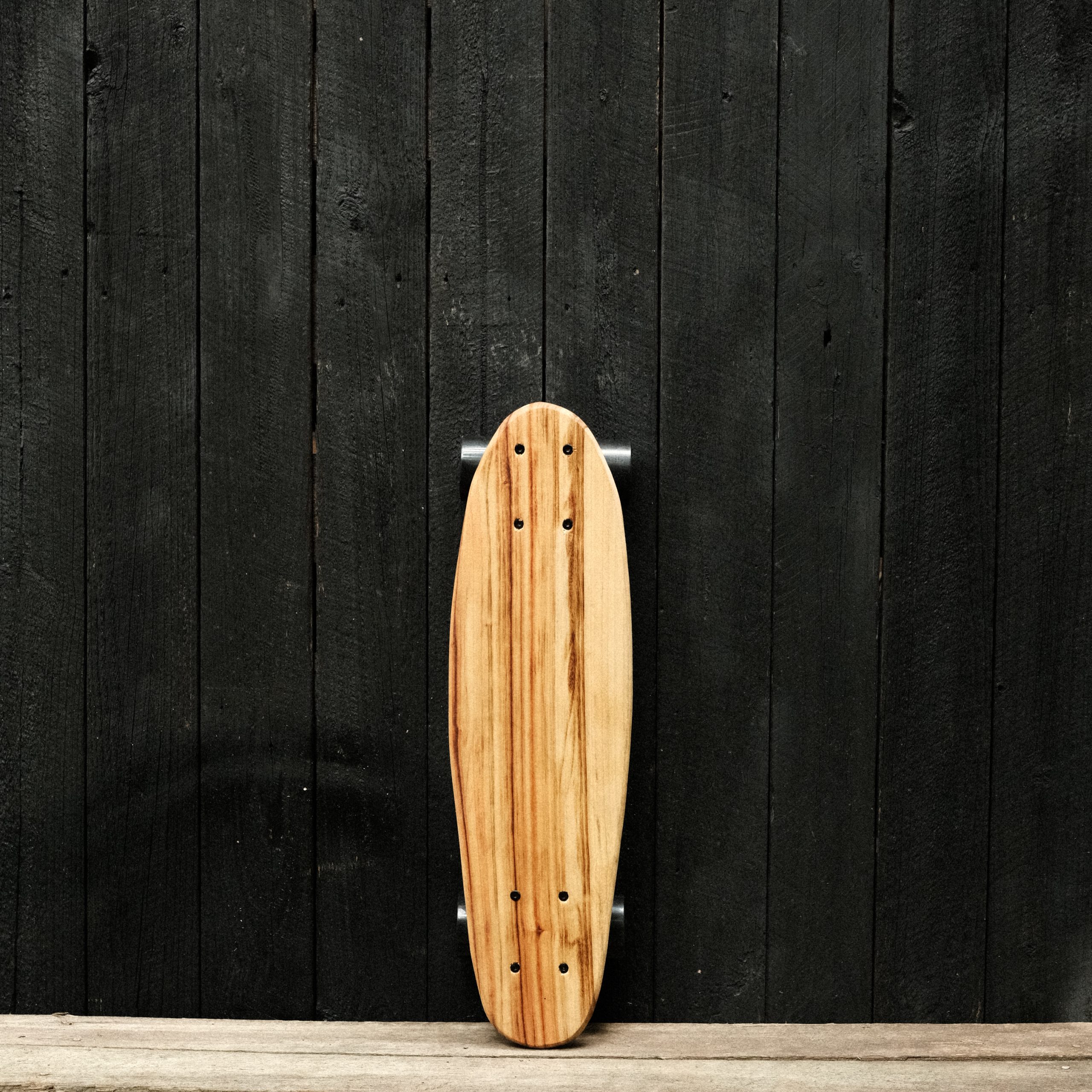 Front of a penny skateboard with trucks and wheels in black